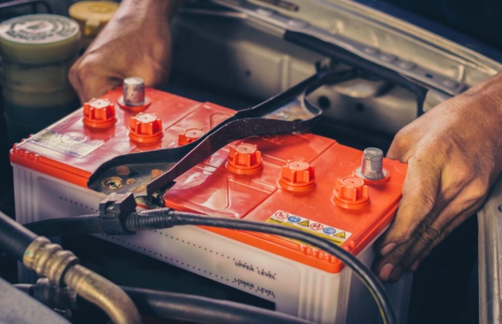 New car battery being put into engine bay